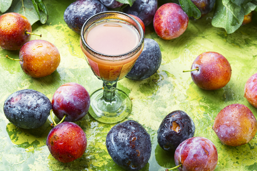 Traditional romanian drink - Plum Liquor, with many plums around the glass