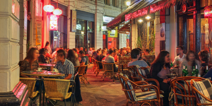 People while eating out in the Old Town Bucharest. The light is diffuse and people are looking happy